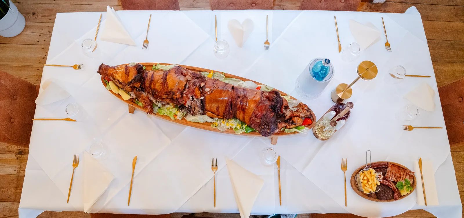 Gedeckte Tafel mit einem ganzen Spanferkel in der Mitte
