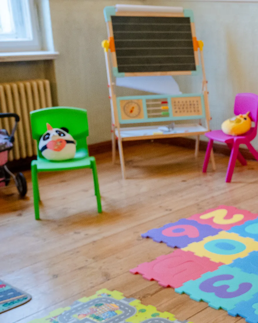 Spielecke mit Maltafel, Kinderstühlen und Spielteppich