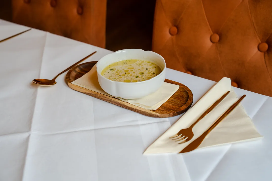 Suppe in einer weißen Schale auf gedecktem Tisch